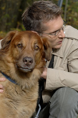 Man with glasses hugging dog