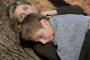 Fototapeta premium Mother and son lying against tree trunk