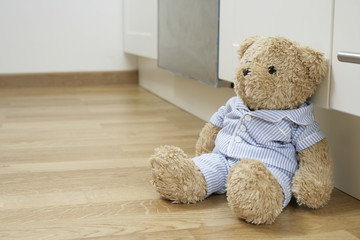 Teddy bear against a kitchen cabinet