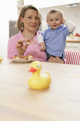 Fototapeta premium Mother feeding son, rubber duck in foreground