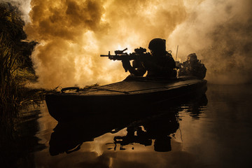 Backlit silhouette of special forces marine operators in military kayak on fire explosion background. Battle operation, bombs exploding
