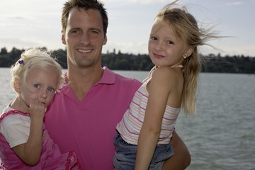 Fototapeta na wymiar Father with his two daughters at the lake, close-up