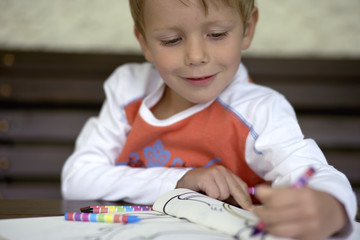Little boy is drawing into a copybook, selective focus