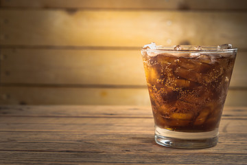 One glass of cola on wood table.
