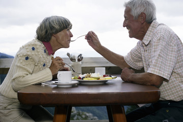 Senior adult couple is sitting on the terrace of a restaurant, selective focus