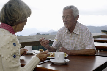 Senior adult couple is sitting on the terrace of a restaurant, selective focus