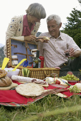 Senior adult couple having a picnic in the mountains, selective focus