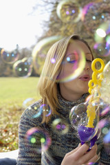 Young woman making soap bubbles, close-up
