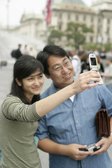 Asian woman is taking a picture of herself and an Asian man, selective focus