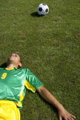 Exhausted Brazilian soccer player lying on grass