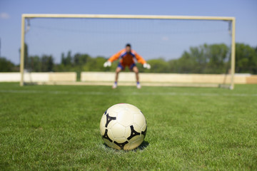 Ball lying on grass, goalkeeper in background