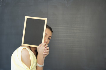 Young woman covering face with a blackboard