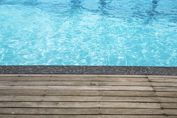 Fototapeta na wymiar Blue swimming pool summer vacation and wooden deck