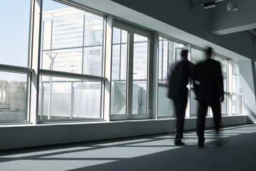 Fototapeta na wymiar Two businessmen walking through a company hall talking about business