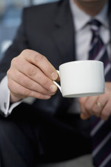 Businessman sitting and holding a cup of coffee in his hand