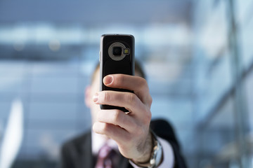 Businessman holding mobile phone to the camera