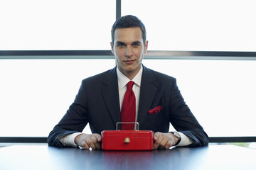 Businessman sitting at a table with a cash box