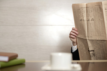 Businessman sitting at desktop, reading a newspaper