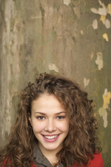 Fototapeta premium Teenage girl with curly hair in front of a log, close-up