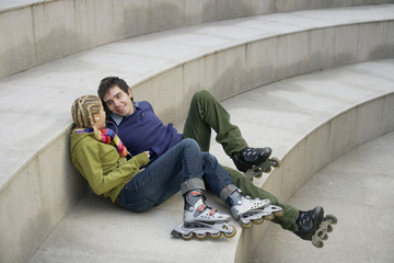 Young couple wearing Inline skates sitting on a staircase