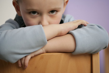 Boy leaning over backrest, sulking