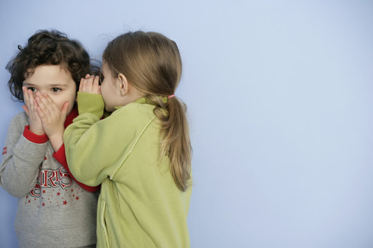 Little girl whispering in girl's ear