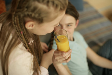 Two friends with braids, one girl drinking a glass of juice