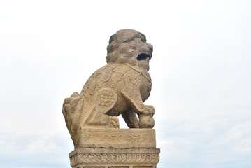 Fototapeta na wymiar Granite lion on cloud sky background.