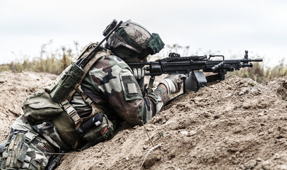 Machine gunner of 1st Marine Infantry Parachute Regiment RPIMA firing from defensive position trench, profile side view - obrazy, fototapety, plakaty