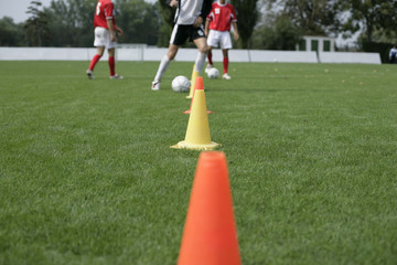 Soccer player running slalom with a football around marks
