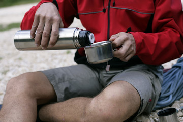 Man sitting outside while having a tee out of a thermos flask