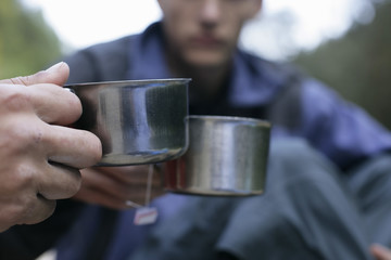 Young men clinking glasses with metallic teacups, selective focus