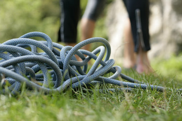 Climbing rope lying on the ground in front of a person (part of), selective focus