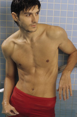 Obraz premium Darkhaired Man leaning against the wall of a Swimming Pool - Baths - Leisure Time