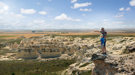 Father and son stand on the rock and look at the horizon line. Castle Rock Badlands. Western Kansas, US