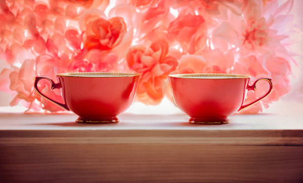 two red teacups pink floral background