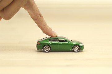 Finger pushing green toy car