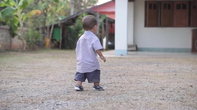 1 year Asian boy  walks and holding Thai money as if he want to go out