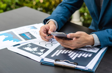 Handsome businessman wearing suit and using modern laptop outdoors and graph finance diagram