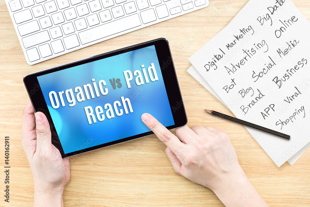 Poster hand using tablet with organic vs paid reach word on screen with list of digital marketing features 