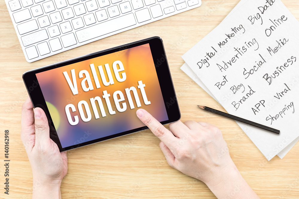 Aufkleber Hand using tablet with Value content word on screen with list of digital marketing features on paper on work table,Online business concept