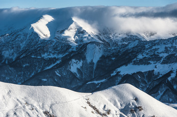 Snowy winter mountains in sun day. Caucasus Mountains, Georgia, from ski resort Gudauri