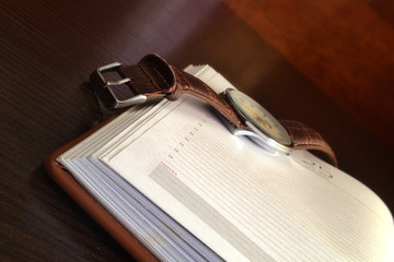 The daily log with the open page and the watch on a table.