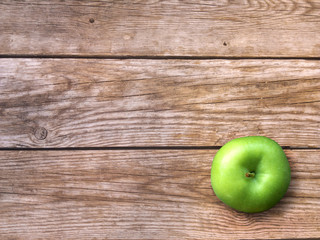 Fresh ripe green apple on natural wooden background. Autumn Wallpaper.