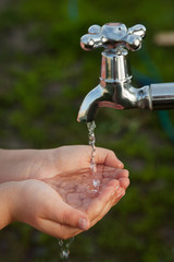 boy washes his hand under the faucet in garden