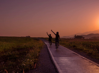 Obraz premium Silhouette of friend on bicycle during sunrise