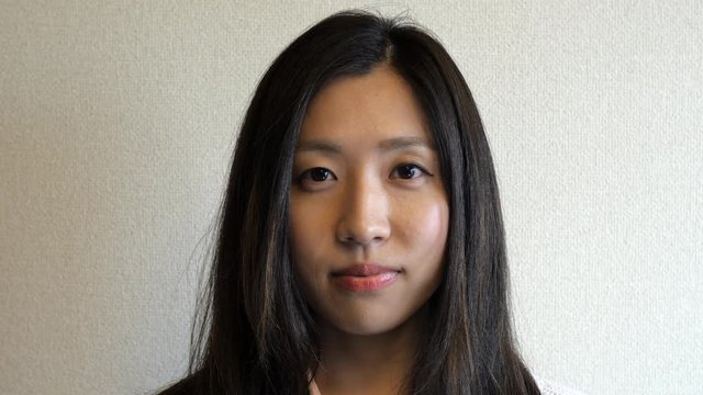 A pretty Japanese woman looks at the camera with a straight face.