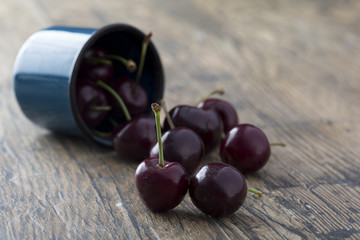 Close-up of cherries in a blue cup on brown background
