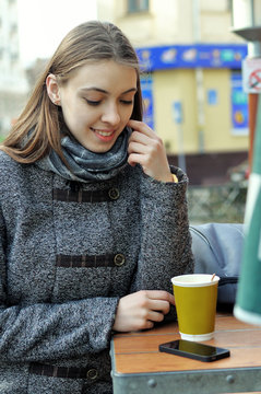 Beautiful girl thinks of drinking coffee or making a phone call