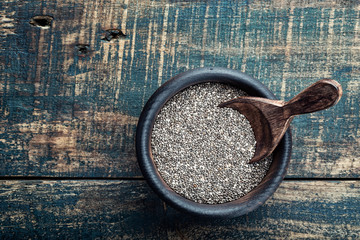 Chia seeds in a wooden bowl on a wooden rustic background